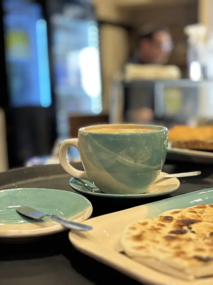 Cappuccino servido en taza de cerámica artesanal celeste en una cafetería