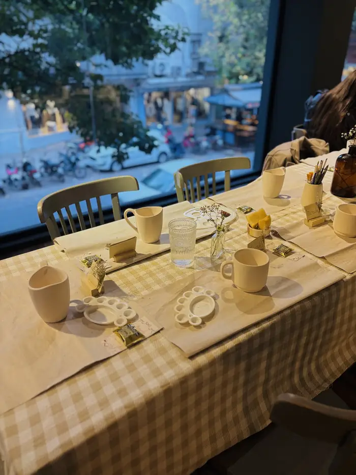 Mesa completa de CERAMIGAS ambientada con mantelería, flores naturales y piezas en crudo